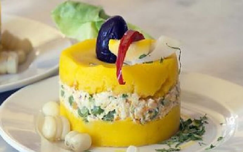 Causa limeña made of yellow potato and filling, topped with olive and chili, typical dish of the Peruvian coast