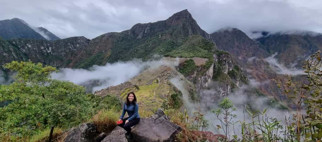 Turista en un mirador de la montaña Machu Picchu con la ciudadela entre la neblina andina