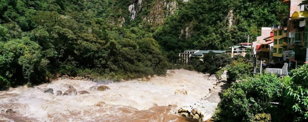 Río Vilcanota atravesando el pueblo de Aguas Calientes rodeado de montañas verdes, Machu Picchu