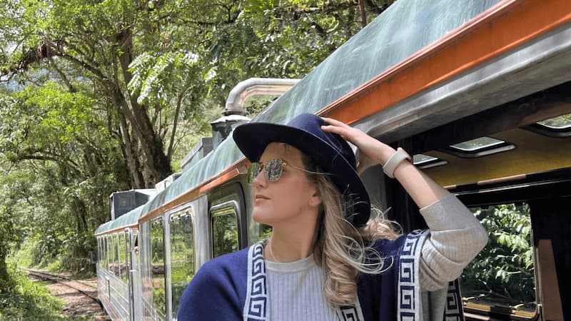 Viajante ao lado do trem rumo a Machu Picchu em meio à vegetação do vale