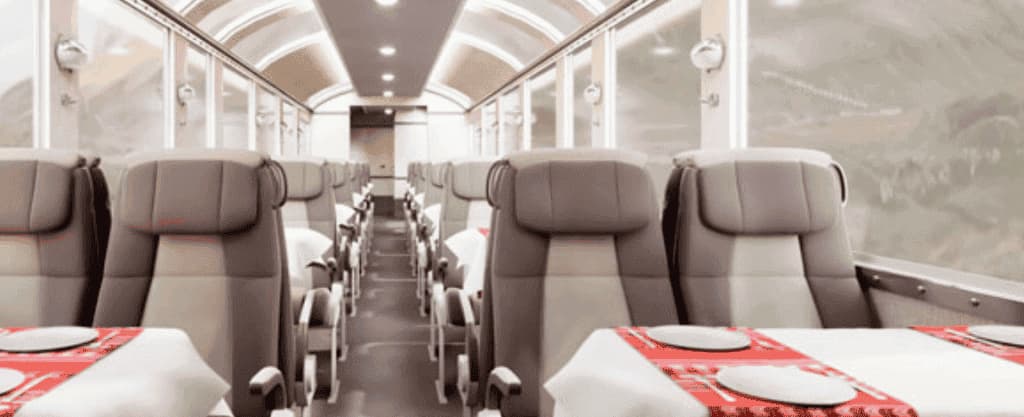 Interior do trem 360° com teto panorâmico e mesas postas a caminho de Machu Picchu