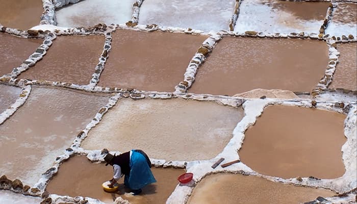 Trabajadora cosechando sal en las Salineras de Maras en el Valle Sagrado