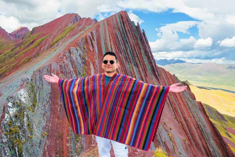 Tourist with Andean poncho at the summit of Pallay Punchu mountain with multicolored stripes in Cusco Peru