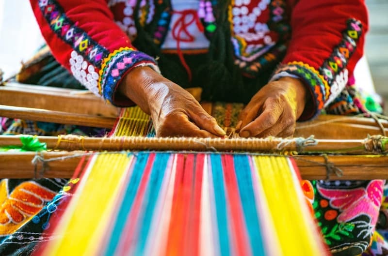 Andean weaver working on a loom at a textile workshop in Chinchero, living culture of the Sacred Valley