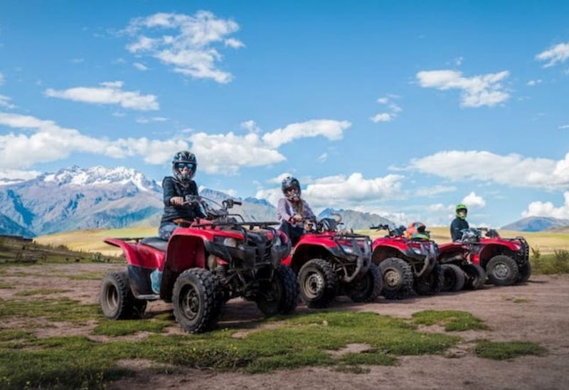 Tourists on ATVs in front of the snow-capped peaks, adventure tour through Maras and Moray in the Sacred Valley