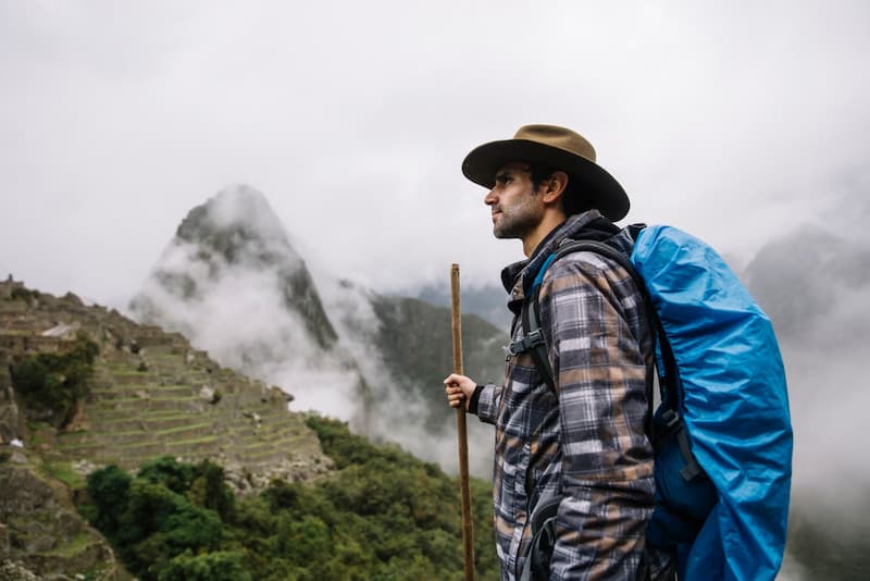Excursionista em frente a Machu Picchu em meio à neblina, uma das formas de chegar de Cusco