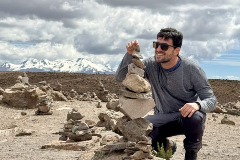 Turista no altiplano de Arequipa empilhando pedras com montanhas nevadas ao fundo