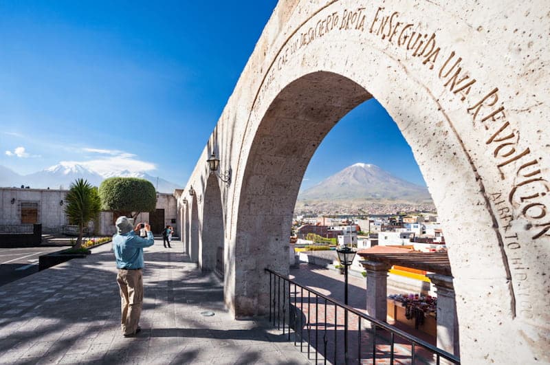 Turista en el altiplano de Arequipa apilando piedras con nevados de fondo
