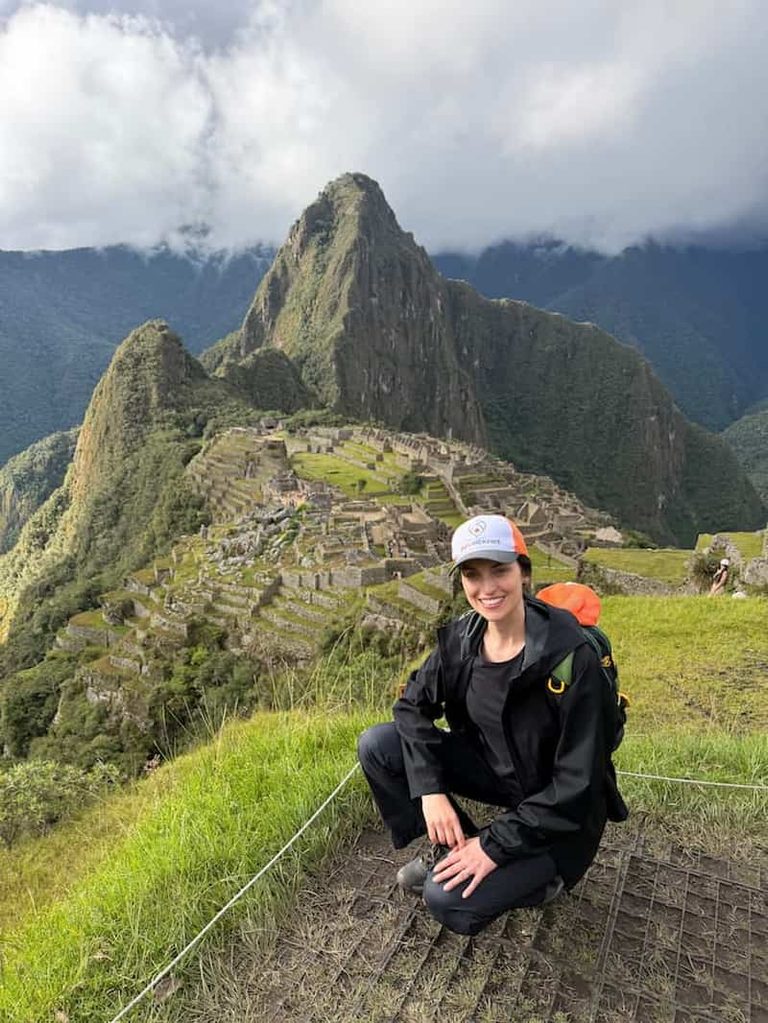 Panoramic view of Machu Picchu with a visitor in front of the citadel and Huayna Picchu Mountain, along Machu Picchu Circuit 1.