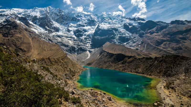 Vista aérea de la Laguna Humantay con aguas turquesas y esmeralda rodeada por los picos rocosos del macizo del Salkantay