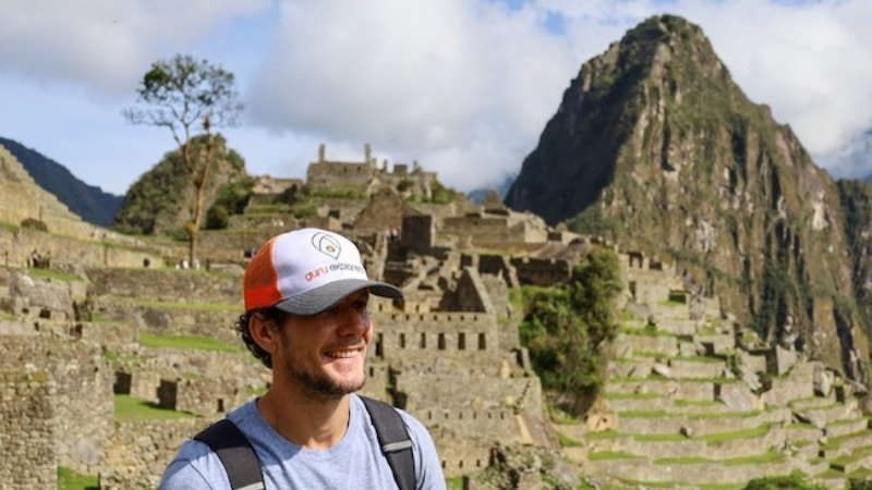 turista de Guru Explorers con gorra en las ruinas de Machu Picchu durante trekking Camino del Inca