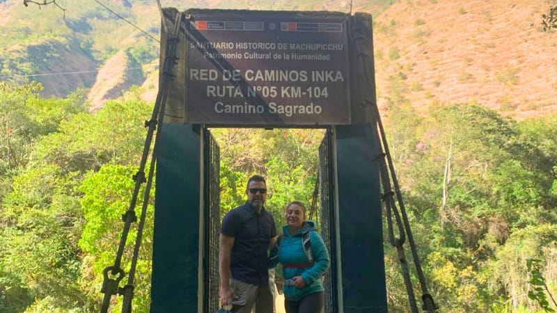Dos viajeros en el arco de inicio del Camino Inca, ruta KM 104, entrada al Santuario Histórico de Machu Picchu